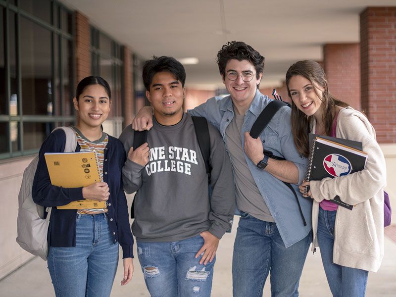 4 students posing in an outdoor hallway.